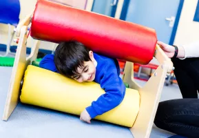 Special needs young child in school sensory room using rolling bars